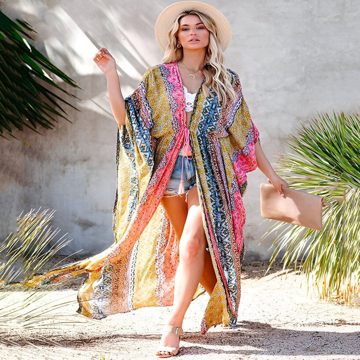 Femme portant un kimono coloré à motifs avec un chapeau de paille. Idéal pour la plage ou un look estival décontracté. Découvrez notre collection de kimonos uniques et originaux.