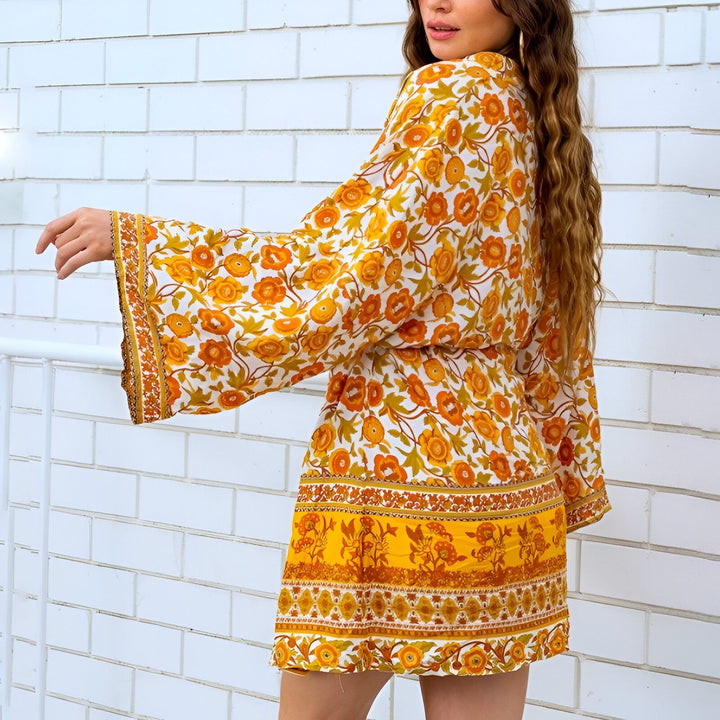 Femme portant un kimono court à motifs floraux orange et jaunes, manches évasées. Vêtement tendance, style bohème. Kimonos à fleurs, collection de kimonos pour femmes.