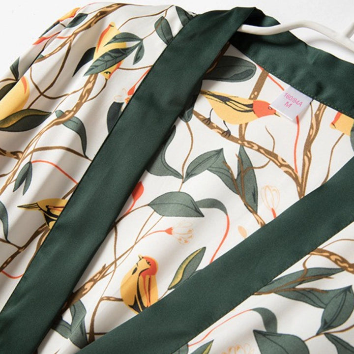 Détail d'un kimono à motifs d'oiseaux et de feuilles. Élégant vêtement de détente avec une bordure verte. Parfait pour se sentir confortable avec style. Disponible dans notre collection de kimonos.