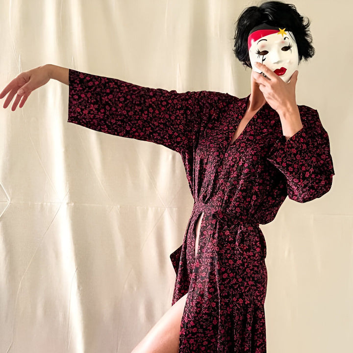 Femme portant un kimono à fleurs rouge et noir, avec un masque blanc de mime. Kimonos pour femmes disponibles en ligne.