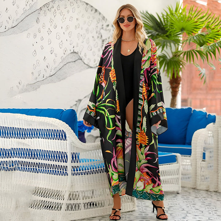 Femme portant un kimono long imprimé floral, en noir et couleurs vives. Kimono parfait pour la plage ou pour ajouter une touche d'élégance à votre tenue. Découvrez notre collection de kimonos uniques.