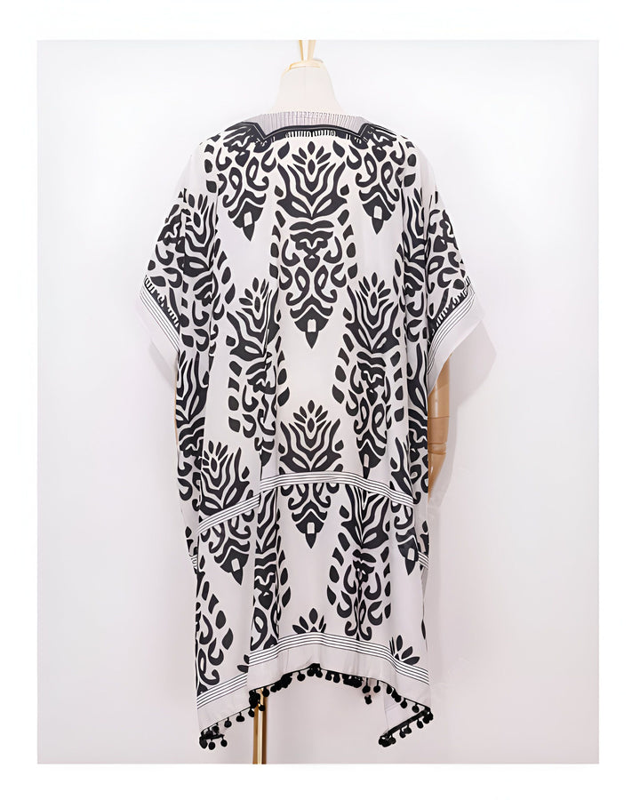 Kimono blanc à motifs noirs sur mannequin. Détail de pompons noirs en bordure. Vêtements de style kimono disponibles à l'achat.