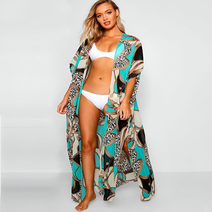 Femme portant un kimono long à motifs turquoise, léopard et chaîne. Kimono fluide idéal comme vêtement de plage. Découvrez notre collection de kimonos tendance.
