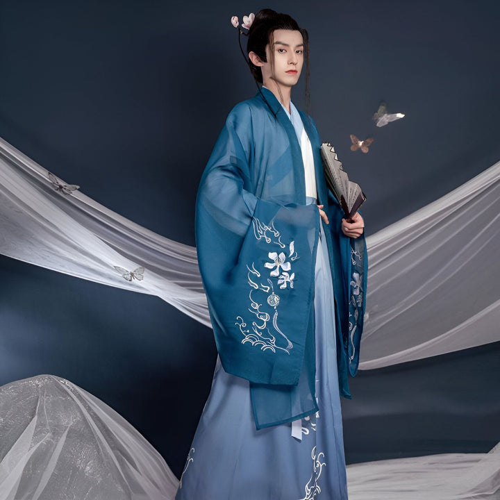 Homme portant un kimono bleu traditionnel avec motifs floraux brodés. Vente de kimonos authentiques et élégants. Idéal pour événements spéciaux et tenues quotidiennes. Découvrez notre collection unique.