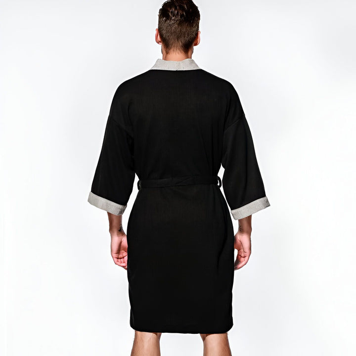 Homme portant un kimono noir à manches courtes et col gris. Vêtement de détente confortable, style japonais. Collection de kimonos modernes pour hommes.