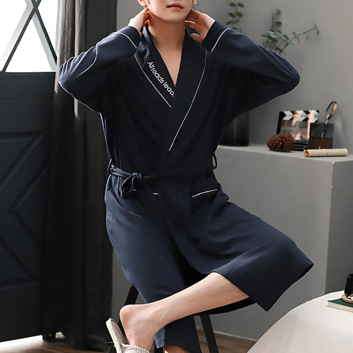 Homme portant un kimono bleu marine avec une ceinture. Kimono pour hommes disponible à l'achat. Parfait pour la détente à la maison ou comme vêtement de nuit élégant.