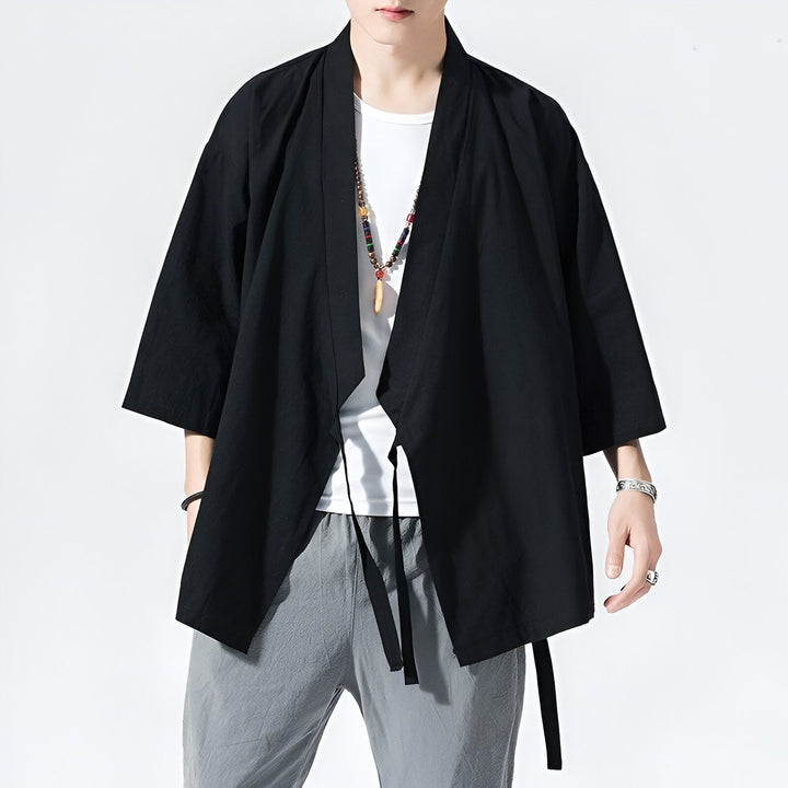Homme portant un kimono noir avec une ceinture, style japonais moderne. Vêtements traditionnels et confortables disponibles à l'achat.