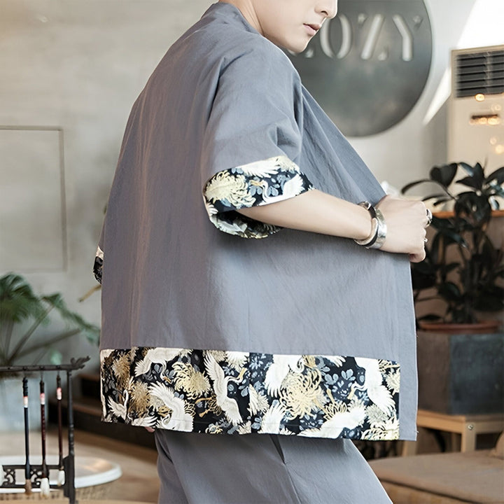Homme portant un kimono gris orné de motifs floraux et d'oiseaux, style japonais moderne. Vêtements traditionnels et tendance.