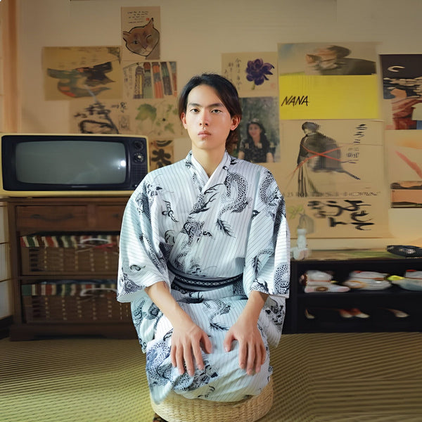 Homme portant un kimono japonais traditionnel blanc à motifs de dragons. Intérieur vintage avec télévision et affiches murales. Vêtements japonais authentiques.