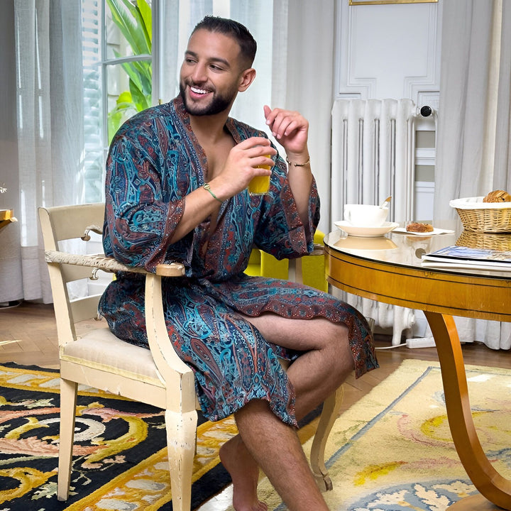 Homme souriant en kimono coloré, appréciant son petit-déjeuner près d'une fenêtre lumineuse. Kimonos pour hommes, vêtements d'intérieur élégants.