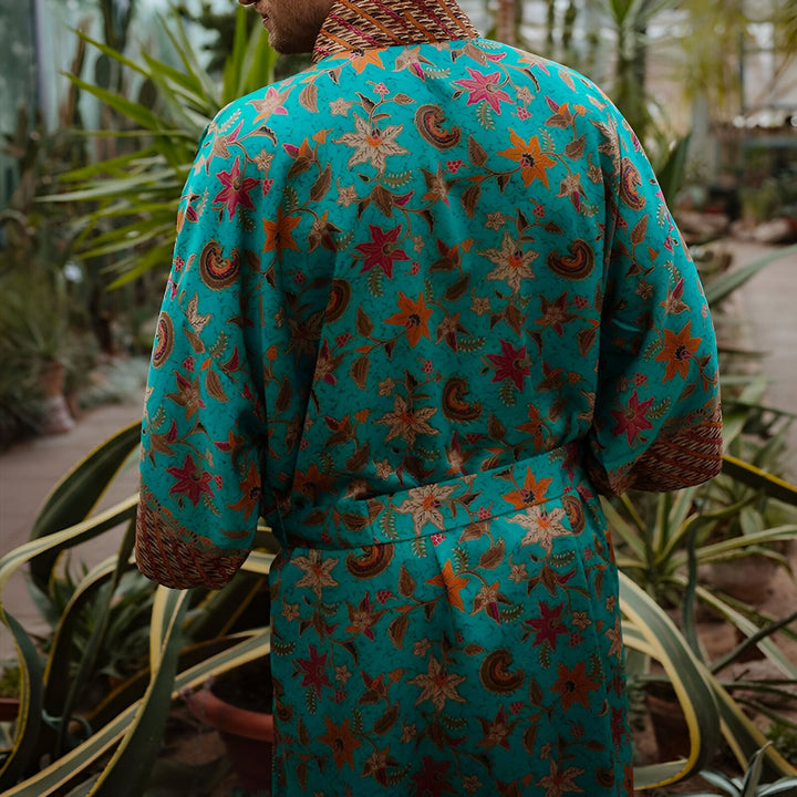 Dos d'un homme portant un kimono turquoise à motifs floraux, vêtement de notre collection. Parfait pour le style et le confort. Découvrez notre gamme de kimonos uniques.