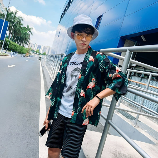 Homme portant un kimono à motifs de flamants roses et de feuilles tropicales. Kimono homme tendance, style estival. Collection de kimonos.