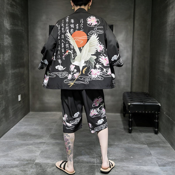 Homme portant un kimono noir avec motif de grue, de soleil, de fleurs de cerisier et de caractères japonais. Ensemble kimono et short assorti. Vêtements japonais traditionnels et modernes. Kimonos à motifs uniques. Mode japonaise.