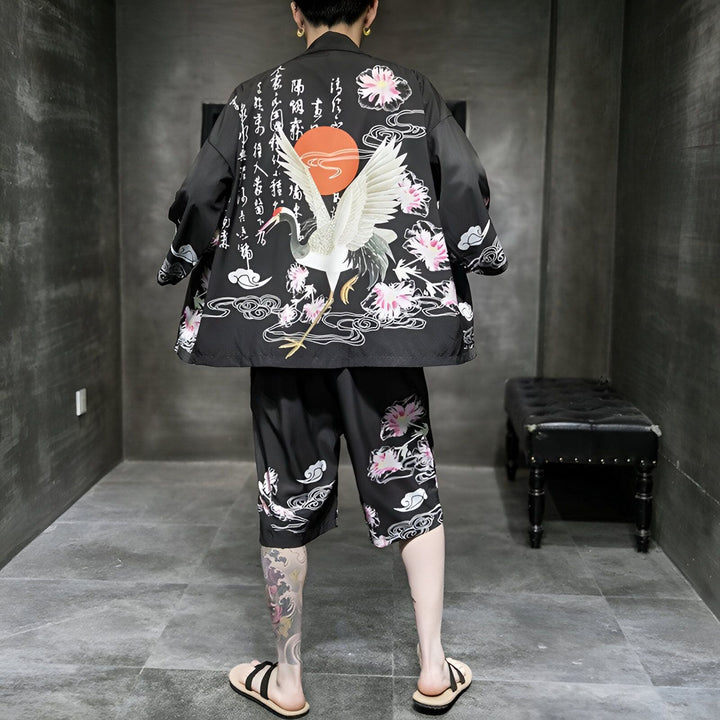 Homme portant un kimono noir avec motif de grue, de soleil, de fleurs de cerisier et de caractères japonais. Ensemble kimono et short assorti. Vêtements japonais traditionnels et modernes. Kimonos à motifs uniques. Mode japonaise.