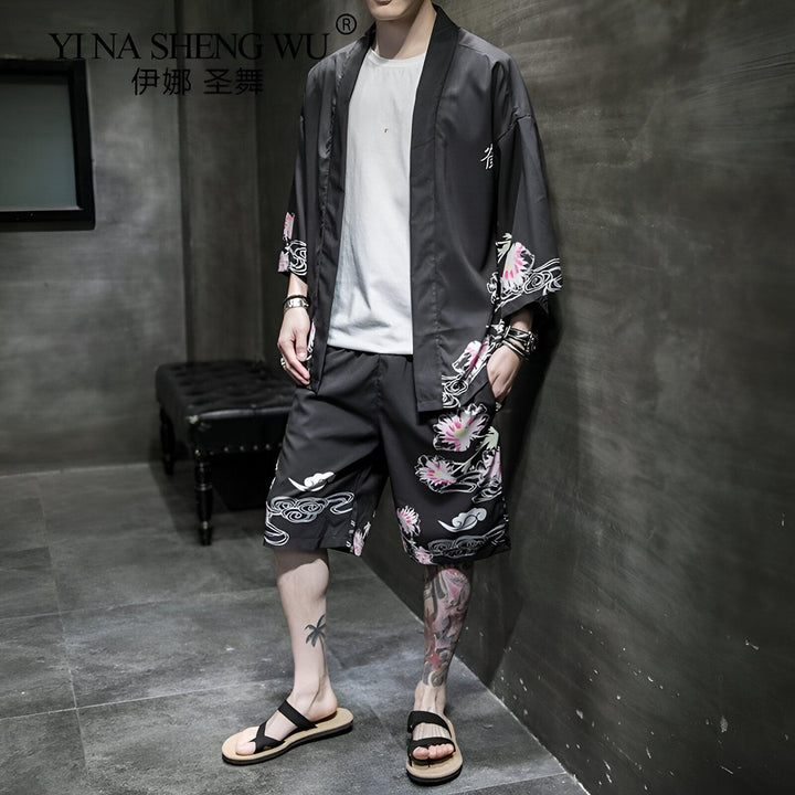 Homme portant un ensemble kimono noir avec des motifs floraux. Kimono d'été à manches courtes et short assorti. Vêtements traditionnels japonais revisités. Boutique de kimonos en ligne.