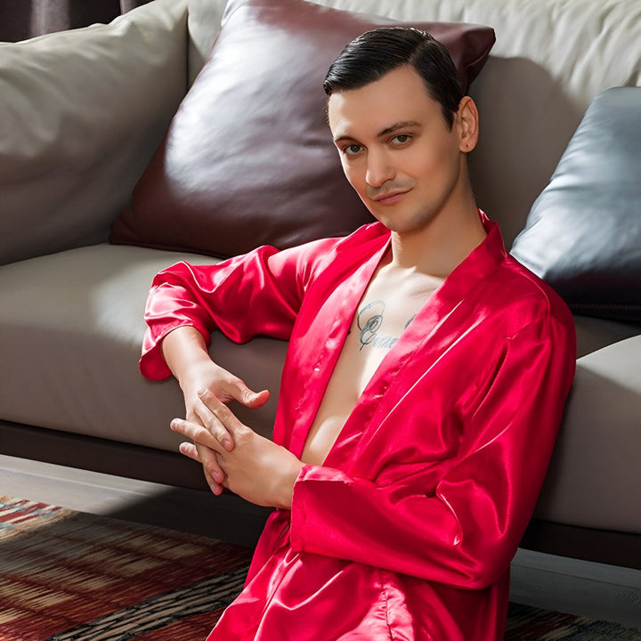Homme portant un kimono rouge en soie, assis près d'un canapé. Kimonos pour hommes, vêtements d'intérieur élégants. Boutique de kimonos japonais traditionnels et modernes.