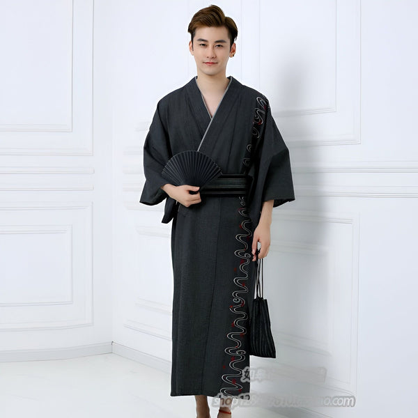 Homme en kimono japonais traditionnel noir avec motif brodé, tenant un éventail noir. Vente de kimonos pour hommes.
