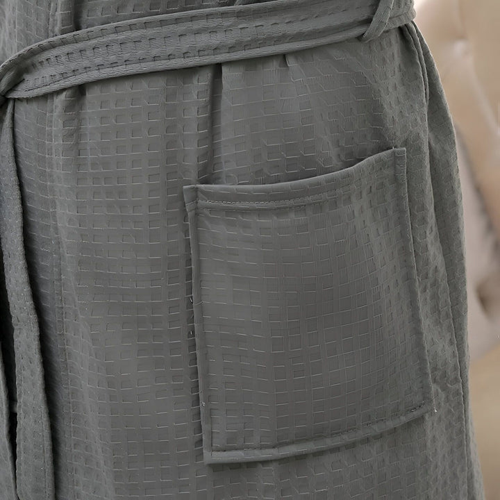 Détail d'un kimono en tissu gaufré gris avec ceinture et poche. Parfait comme peignoir confortable ou vêtement d'intérieur élégant. Découvrez notre collection de kimonos.