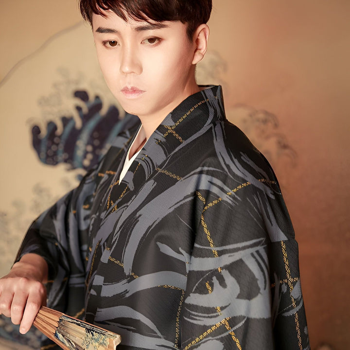 Homme portant un kimono japonais noir et gris avec un éventail. Découvrez notre collection de kimonos traditionnels et modernes.