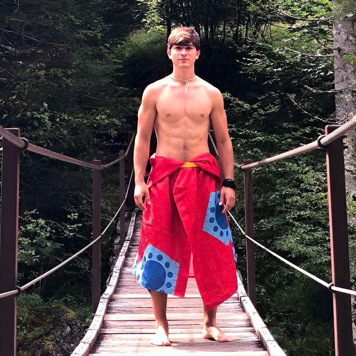 Homme torse nu portant un kimono rouge avec motifs bleus sur un pont en bois. Kimonos uniques et originaux à découvrir.