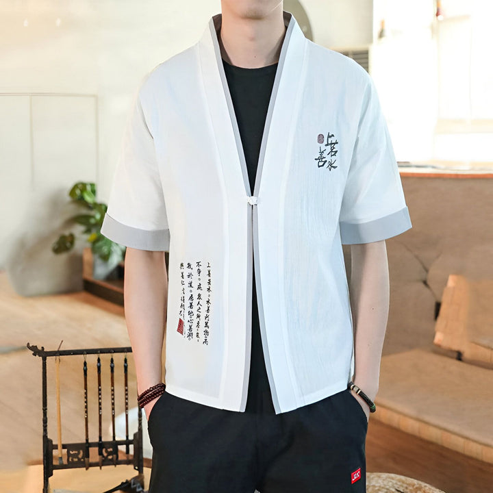 Homme portant un kimono d'été blanc avec des motifs calligraphiques. Vêtement japonais traditionnel, idéal pour la saison estivale. Découvrez notre collection de kimonos.