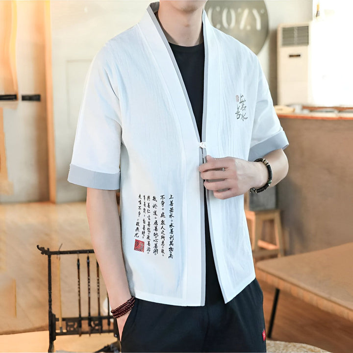Homme portant un kimono blanc à manches courtes avec des détails gris et des motifs calligraphiques noirs. Vêtements japonais traditionnels.