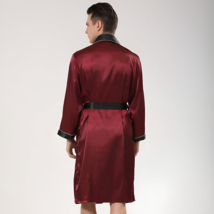 Homme portant un kimono bordeaux, vu de dos. Kimono en satin avec ceinture noire et finitions contrastées. Vêtements d'intérieur élégants, style japonais.