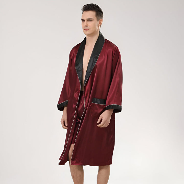 Homme portant un kimono bordeaux en satin avec bordure noire, vêtement de détente élégant. Kimonos pour hommes disponibles à l'achat.