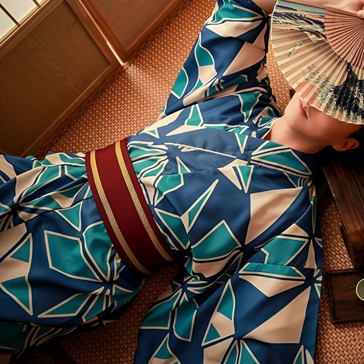 Femme portant un kimono bleu et blanc avec une ceinture obi rouge. Elle tient un éventail devant son visage. Kimonos traditionnels japonais à vendre.