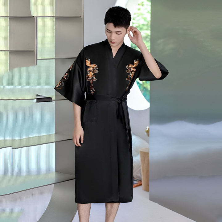 Homme portant un kimono noir avec broderies dorées. Vêtement de détente élégant. Kimonos pour hommes disponibles.