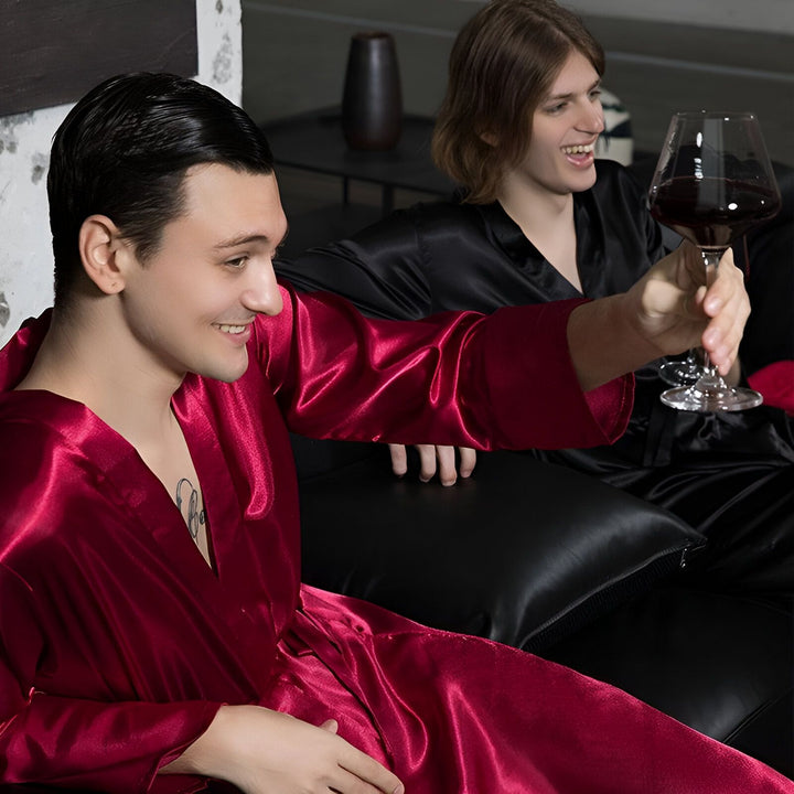 Deux hommes détendus en kimonos de soie, rouge et noir, savourant un verre de vin. Vêtements d'intérieur élégants et confortables.