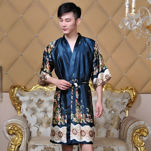 Homme portant un kimono bleu en soie avec des motifs floraux, devant un fauteuil doré. Vente de kimonos pour hommes.