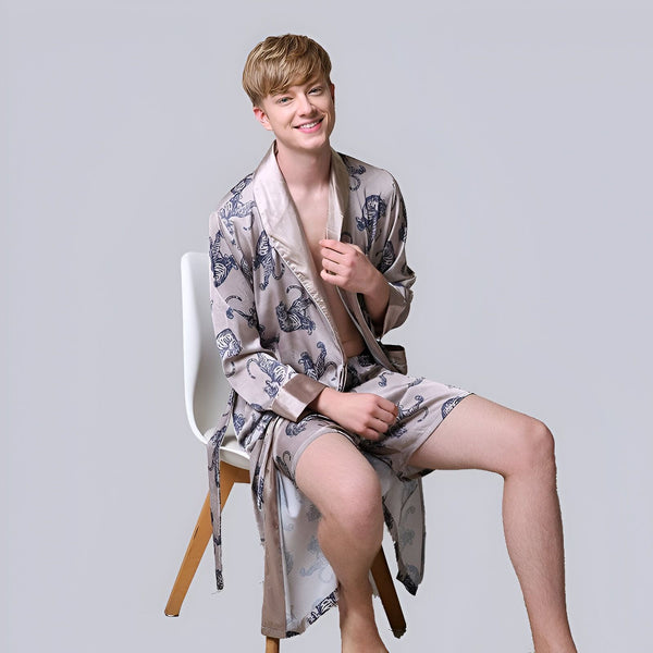 Homme souriant portant un kimono beige à motifs de tigres bleus, assis sur une chaise. Vêtements de détente de style japonais, peignoir kimono, vente de kimonos en ligne.