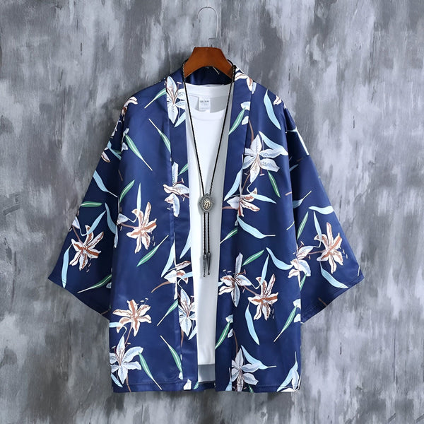 Kimono bleu marine à motifs floraux blancs et marron, suspendu à un cintre. Un t-shirt blanc et un collier pendentif complètent le look. Notre collection de kimonos pour un style unique et tendance.