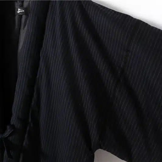 Détail d'un kimono rayé noir, vêtement traditionnel japonais. Texture textile, style et élégance. Découvrez notre collection de kimonos uniques.