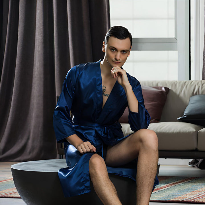 Homme assis portant un kimono bleu en soie. Élégance et confort pour vos moments de détente. Découvrez notre collection de kimonos.