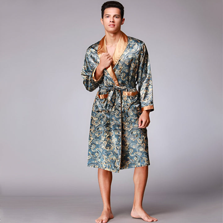 Homme portant un kimono en soie bleu et or. Kimono à motifs paisley, avec bordure dorée. Vêtements d'intérieur élégants, peignoir de luxe. Découvrez notre collection de kimonos.