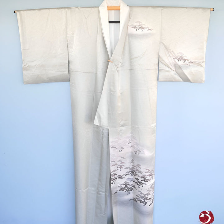 Kimono japonais blanc avec motifs d'arbres, suspendu sur un cintre. Vêtement traditionnel idéal pour une élégance raffinée. Découvrez notre collection de kimonos uniques.