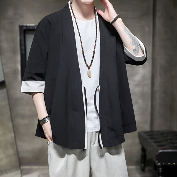 Homme portant un kimono noir décontracté avec des manches trois quarts et des revers blancs. Collier à pendentif. Vêtements de style japonais en vente.