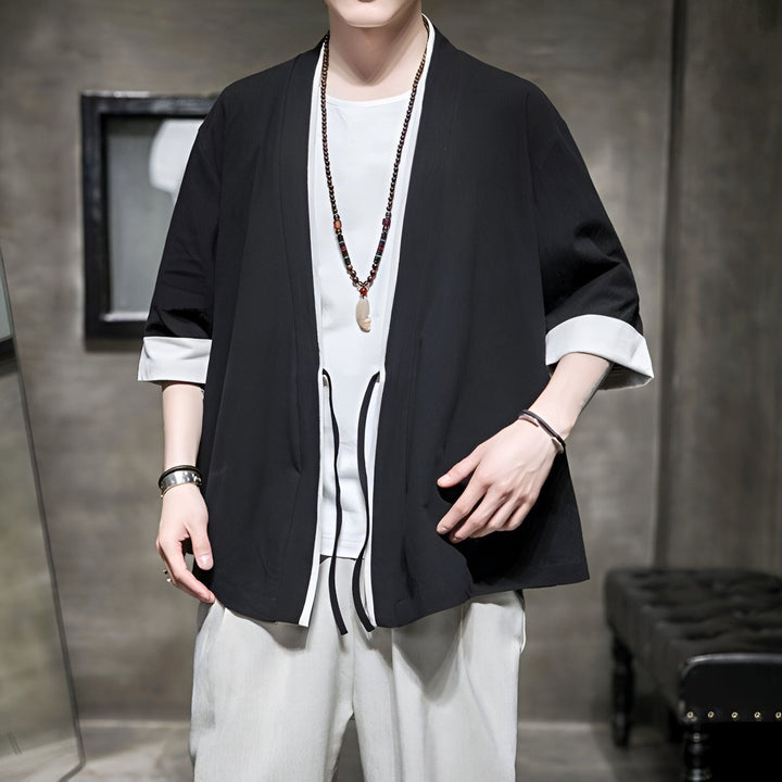 Homme portant un kimono noir avec des manches trois-quarts et des bordures blanches. Style décontracté et moderne. Kimonos disponibles à l'achat.
