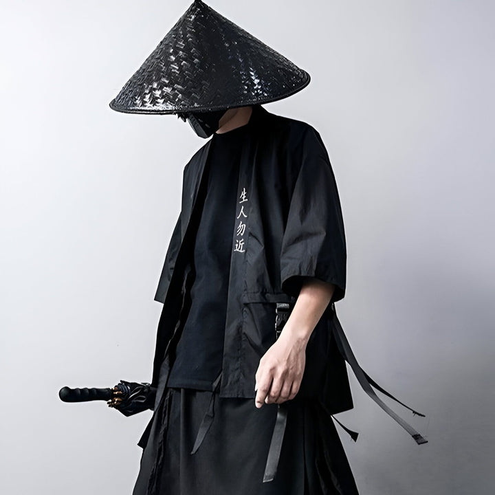Homme portant un kimono noir avec un chapeau conique traditionnel. Vêtement japonais élégant, disponible dans notre boutique. Découvrez notre collection de kimonos uniques.