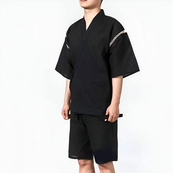 Homme portant un kimono noir décontracté avec un short assorti. Vêtements traditionnels japonais revisités. Kimono pour hommes disponible à l'achat.
