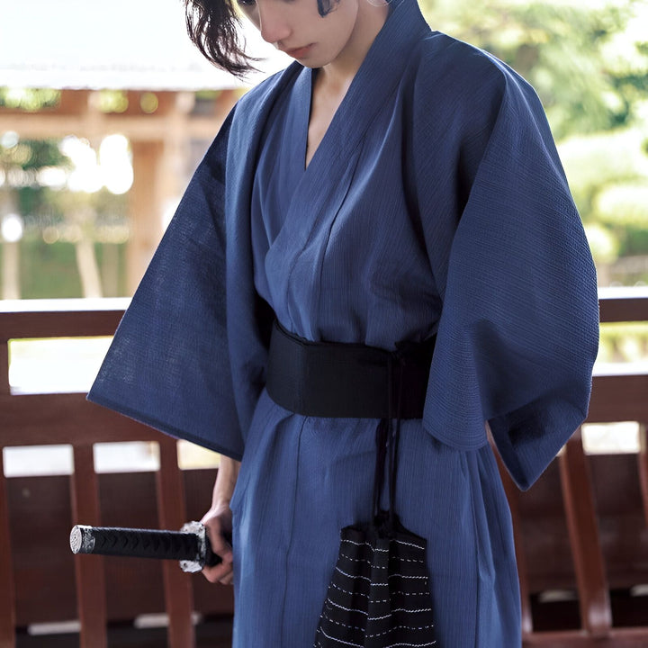 Homme en kimono bleu tenant un sabre. Kimonos traditionnels japonais en vente. Découvrez notre collection de kimonos de qualité.