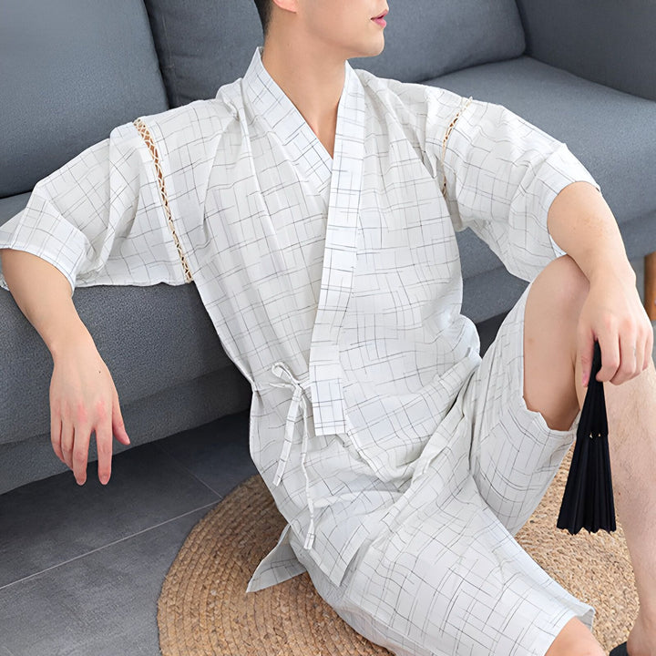Homme portant un kimono à carreaux blanc et gris clair avec un éventail noir. Vêtements de détente japonais traditionnels. Kimonos à vendre.