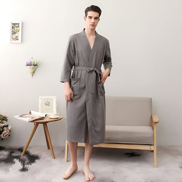 Homme portant un kimono gris confortable avec ceinture. Idéal comme vêtement d'intérieur relaxant. Découvrez notre collection de kimonos pour hommes.
