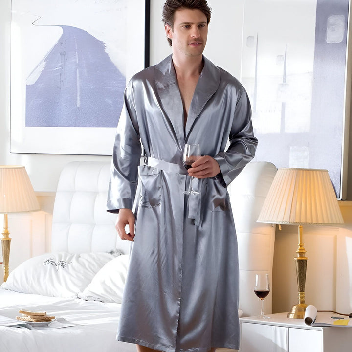 Homme portant un kimono de chambre gris en soie avec un verre de vin. Élégance et confort pour la maison. Découvrez notre collection de kimonos de qualité supérieure.
