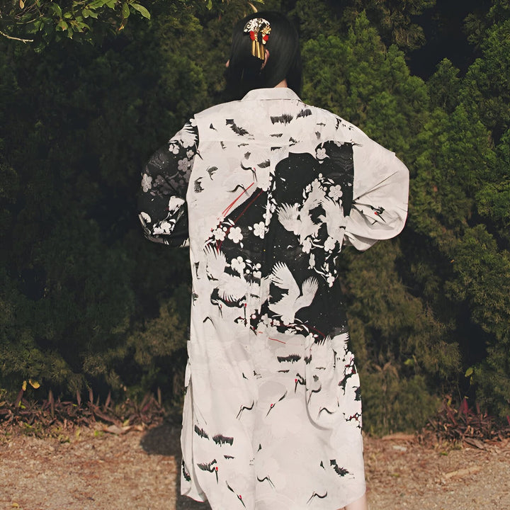 Femme portant un kimono imprimé avec des motifs de grues japonaises en noir et blanc. Vente de kimonos en ligne. Accessoires pour cheveux traditionnels.