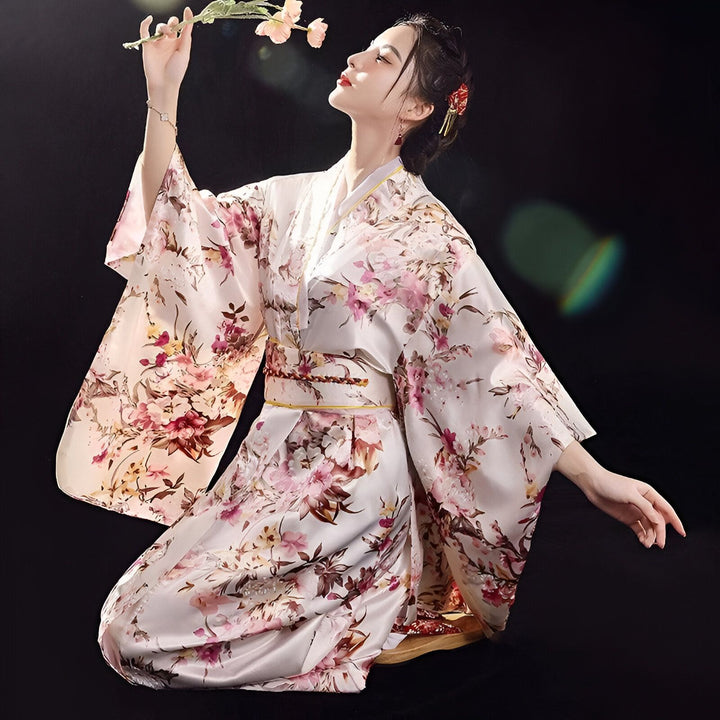 Femme portant un kimono fleuri, genoux au sol. Élégance et tradition japonaise. Découvrez notre collection de kimonos uniques.