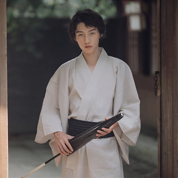 Homme asiatique en kimono blanc traditionnel tenant un parapluie noir. Vêtements japonais authentiques à vendre. Style et élégance japonaises. Découvrez notre collection de kimonos.