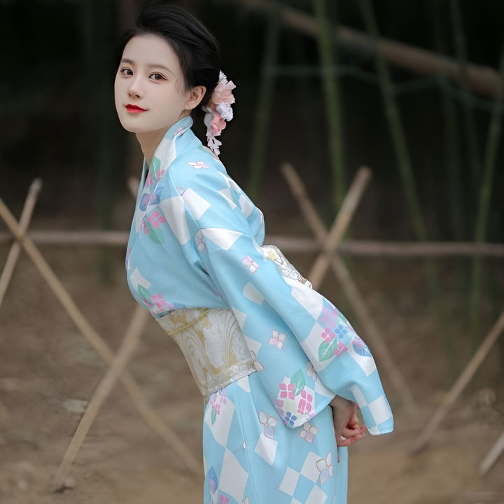 Femme portant un kimono bleu à motifs floraux et géométriques. Kimonos traditionnels japonais disponibles à l'achat.
